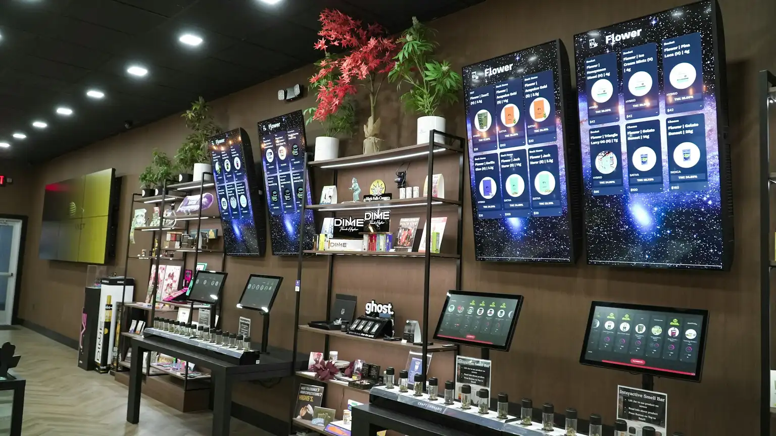 Digital menu boards above a dispensary product display listing flower categories and prices