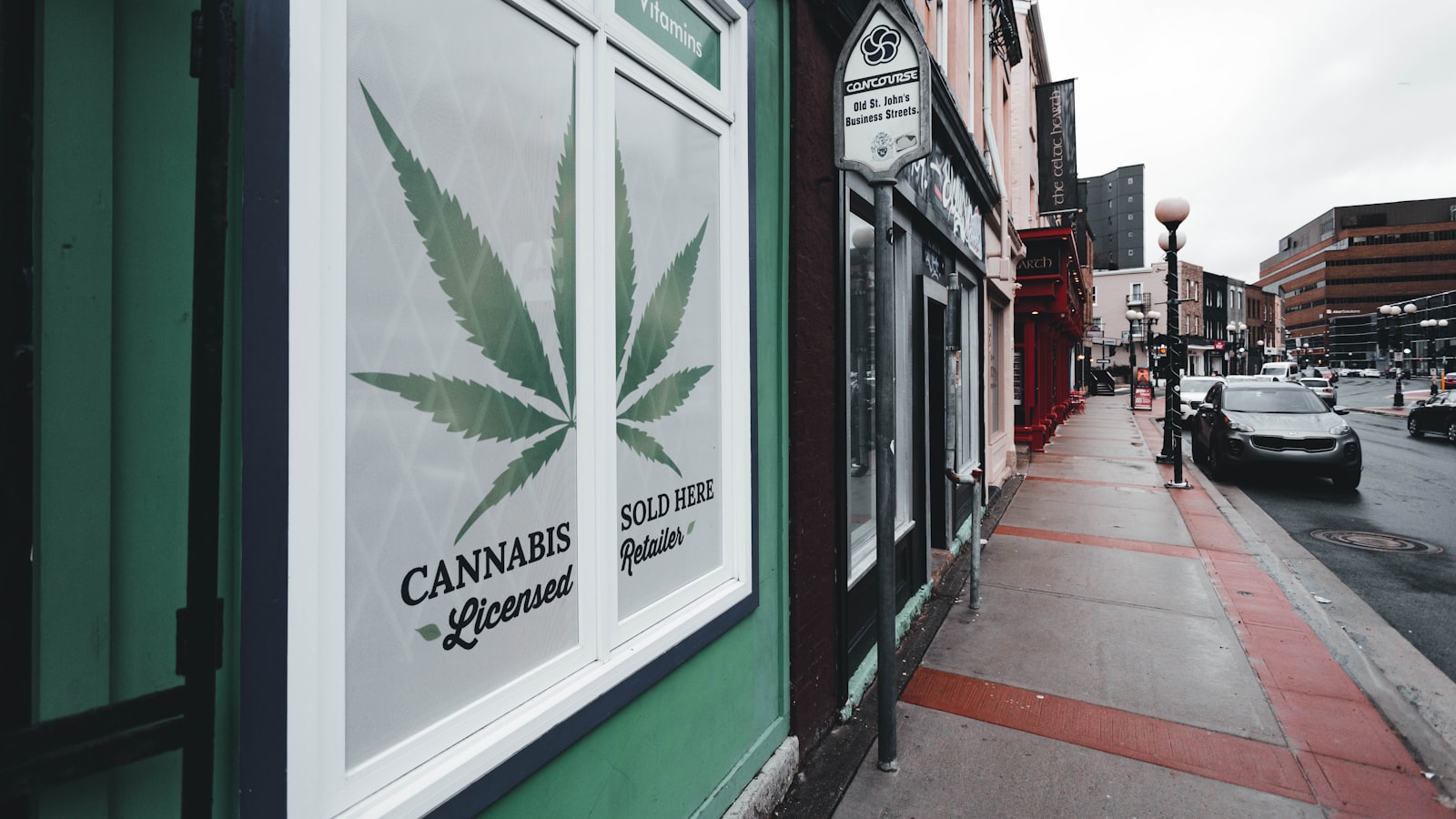A licensed cannabis retailer window sign reading Cannabis Licensed Sold Here on a downtown street